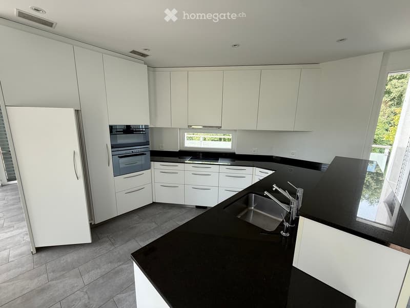 Modern kitchen with white cabinets, black countertops, stainless steel sink, and built-in appliances.