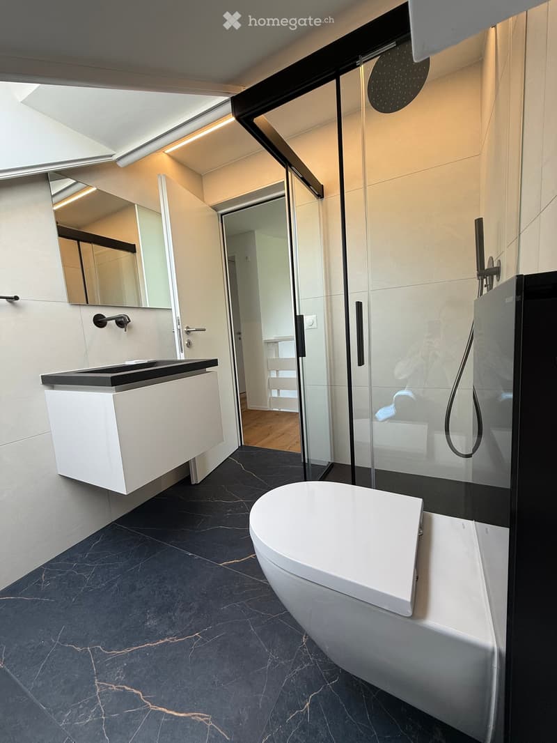 Modern bathroom with a white bathtub, sleek sink, large mirror, and glass-enclosed shower area.