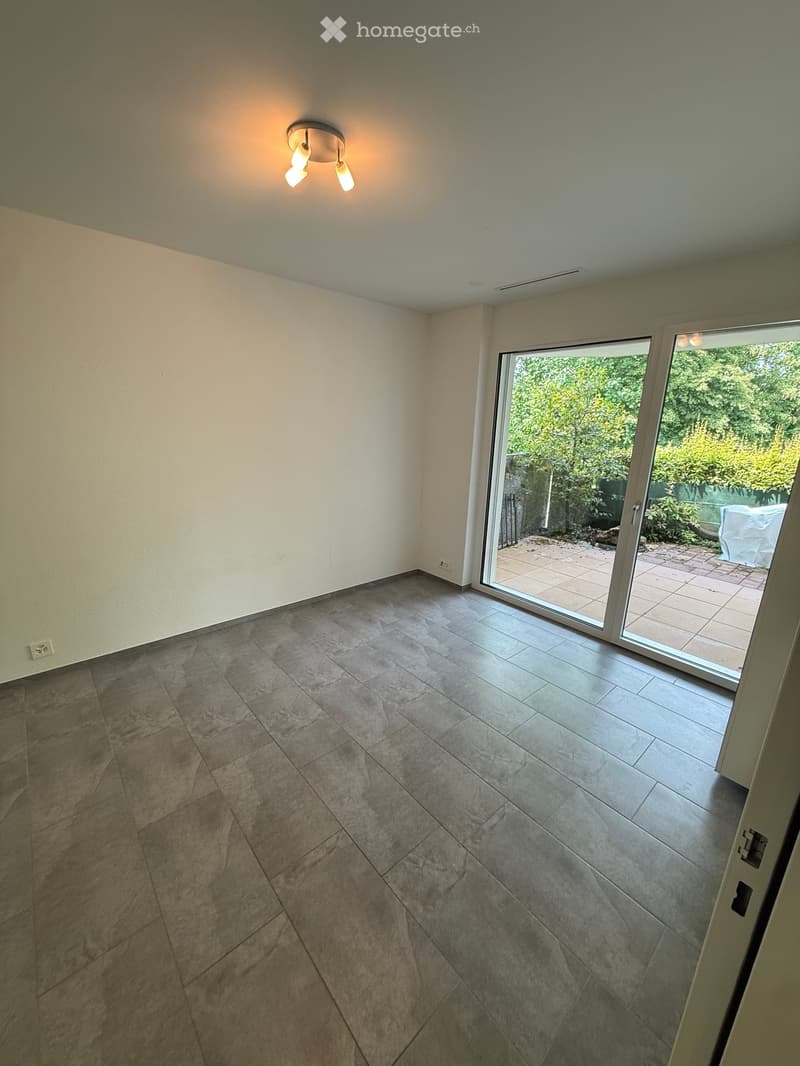 Empty room with tiled floor, white walls, and a sliding glass door leading to an outdoor patio.