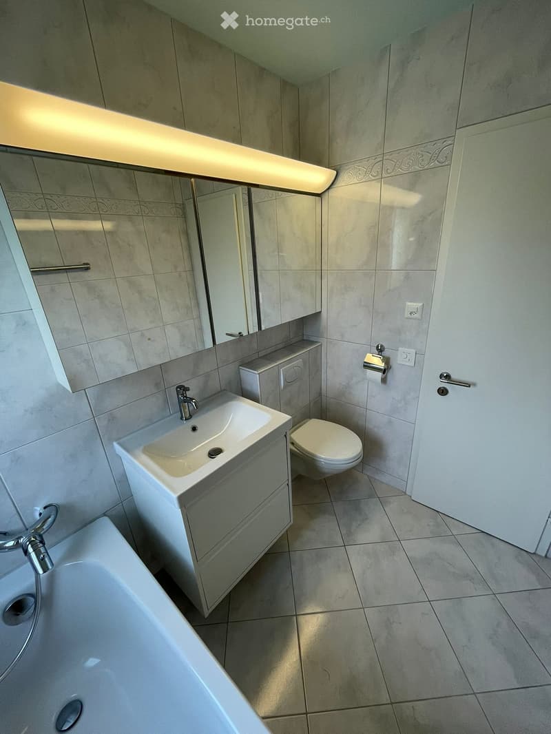 Bathroom with bathtub, sink, toilet, mirror, and tiled floor