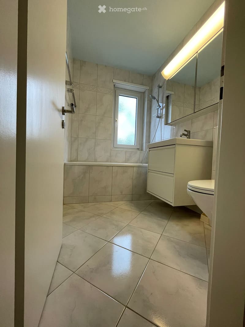 Bathroom with bathtub, sink, toilet, mirror, and window