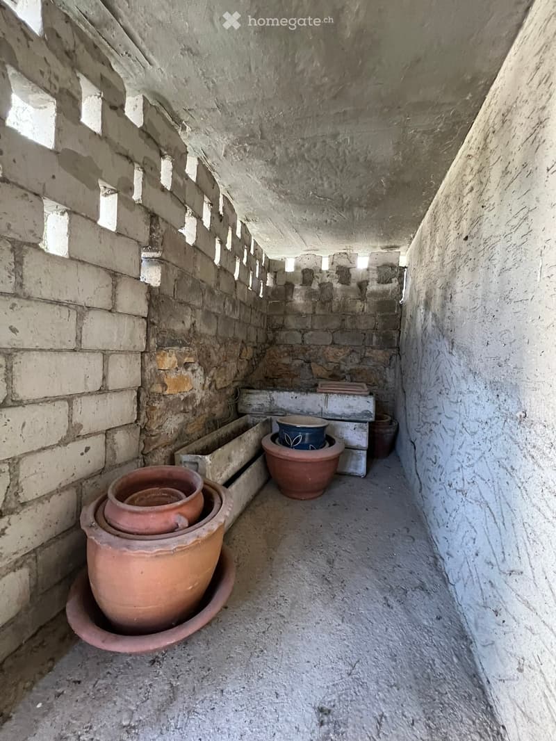 A narrow stone-walled corridor with several large terracotta pots stacked on the floor, some placed on a stone ledge.