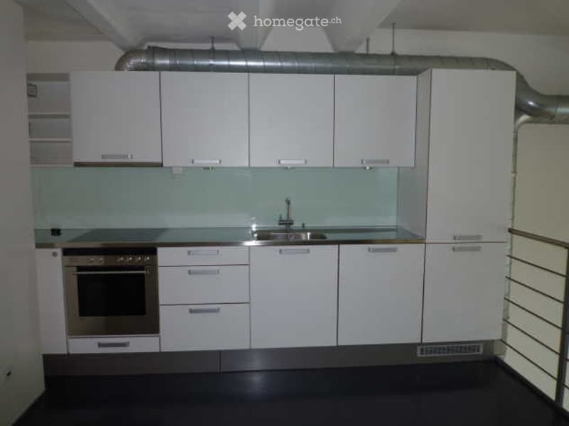 Modern kitchen with white cabinets, stainless steel sink, and built-in oven. Clean and minimalist design with a glass backsplash.