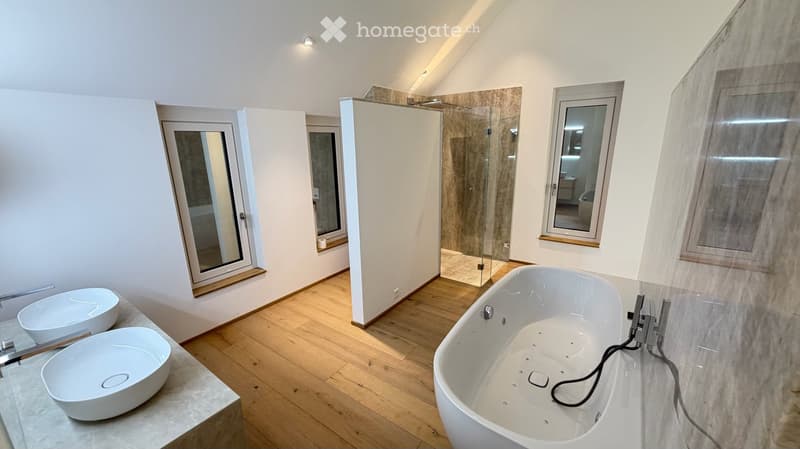 Modern bathroom with a freestanding bathtub, two sinks, a glass-enclosed shower, and large windows.