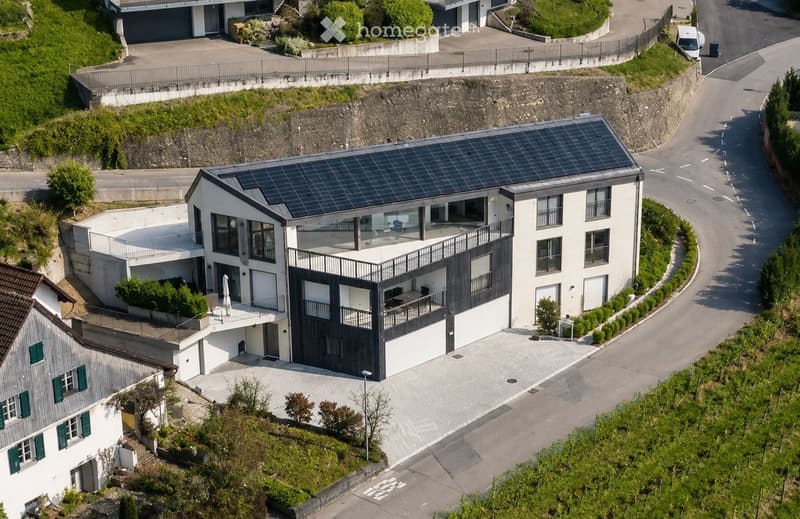 Modern two-story house with white exterior, solar panels on the roof, garage, and parking area.