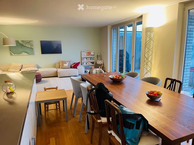A modern living and dining area with a sofa, coffee table, dining table, chairs, and decorative items.