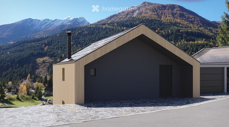 Modern two-story building with a flat roof, dark grey walls, and a garage with solar panels on the roof, set against a backdrop of mountains and trees.