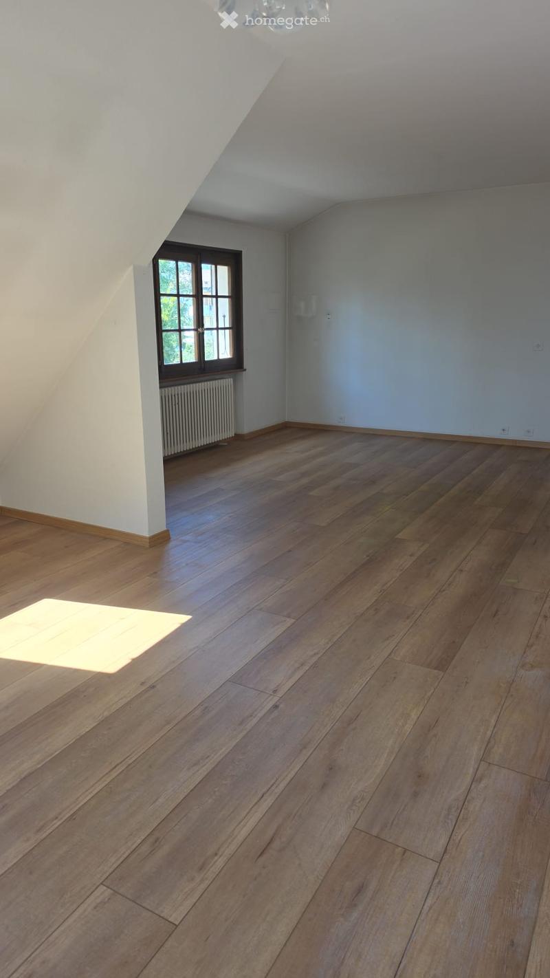Empty room with wooden flooring, white walls, and a window with a radiator below it.