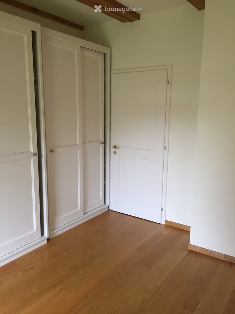 room with white walls, wooden floor, white closets, and an exit door