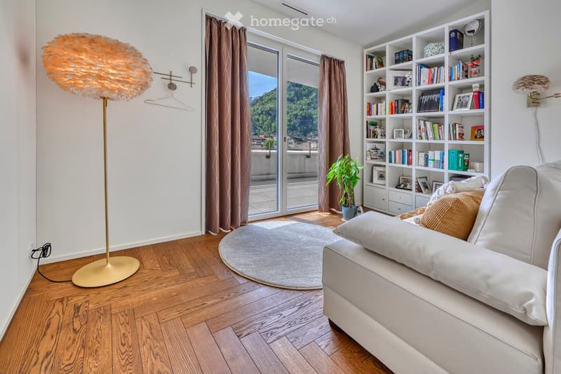 large white sofa, parquet flooring, white ceiling, round rug, floor lamp, full length windows with curtains, balcony, white bookcase, mountain view