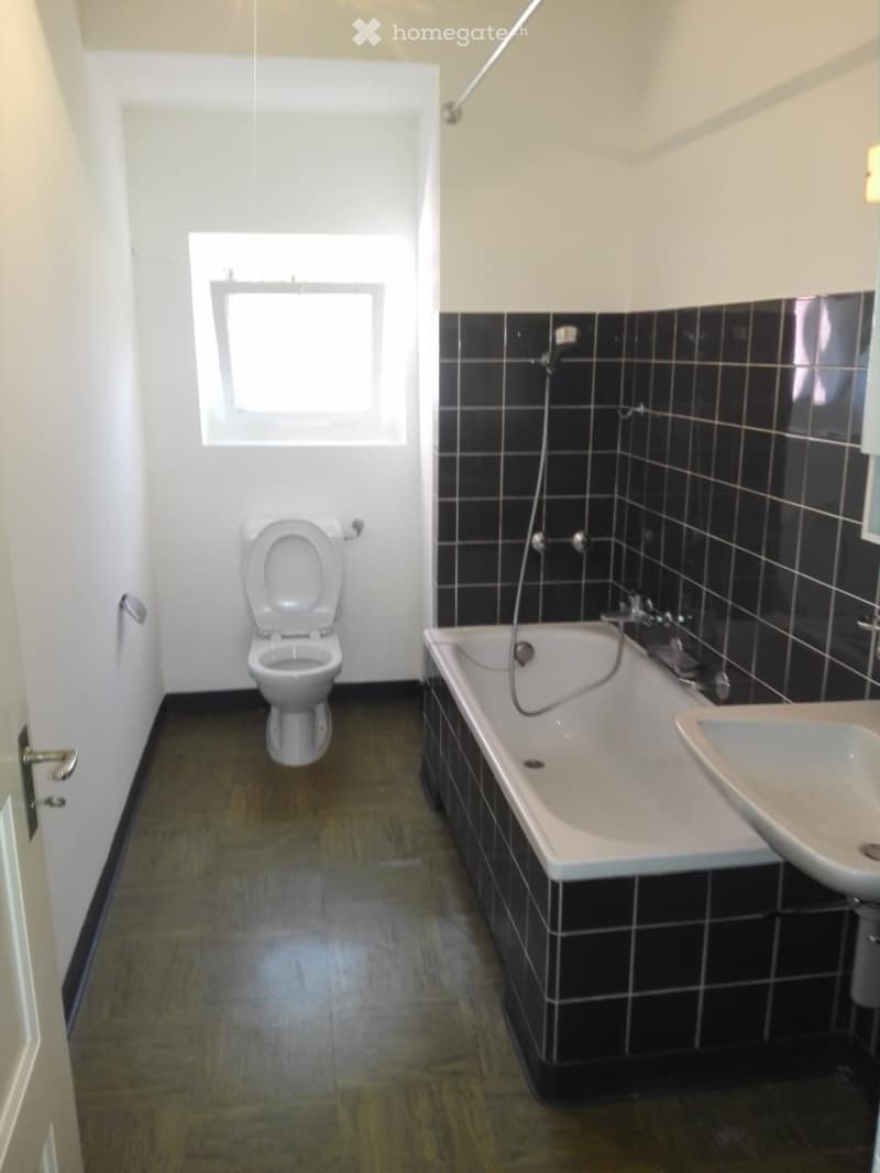 Bathroom with white tiles, bathtub, sink, and toilet.