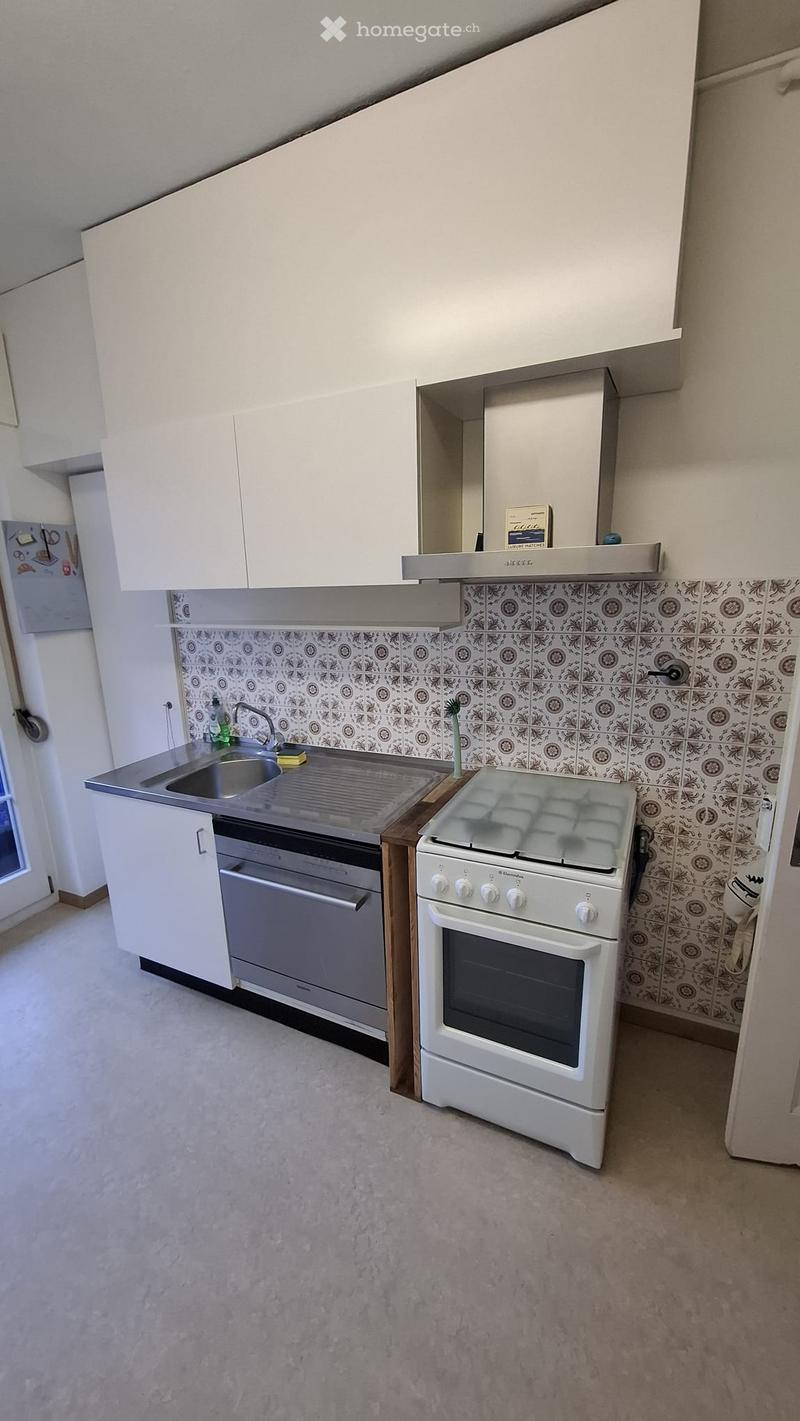 Modern kitchen with white cabinets, stainless steel sink, oven, and stove. The backsplash features a patterned tile design.