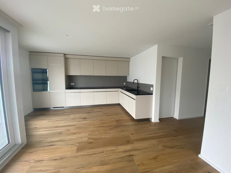 Empty room with light-colored cabinets, a sink, and wooden flooring.