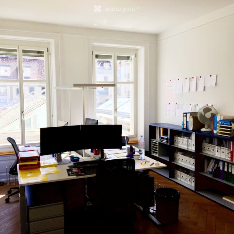 Desk with dual monitors, keyboard, mouse, office chair, shelves, bookshelf, files