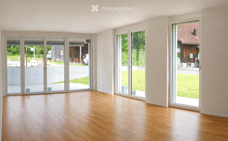 Empty room with wooden flooring and large glass doors leading to an outdoor area.