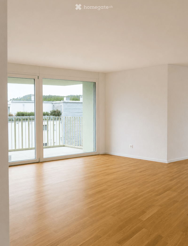 Empty room with light wooden flooring and large sliding glass doors leading to a balcony.