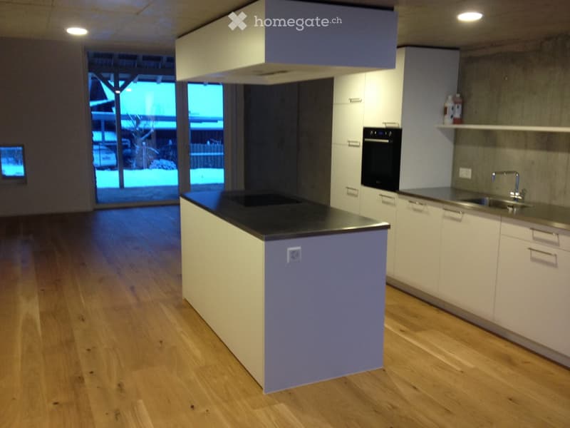 Modern kitchen with white cabinets, dark countertop, sink, faucet, and built-in oven. Large sliding glass door leads to outdoor area.