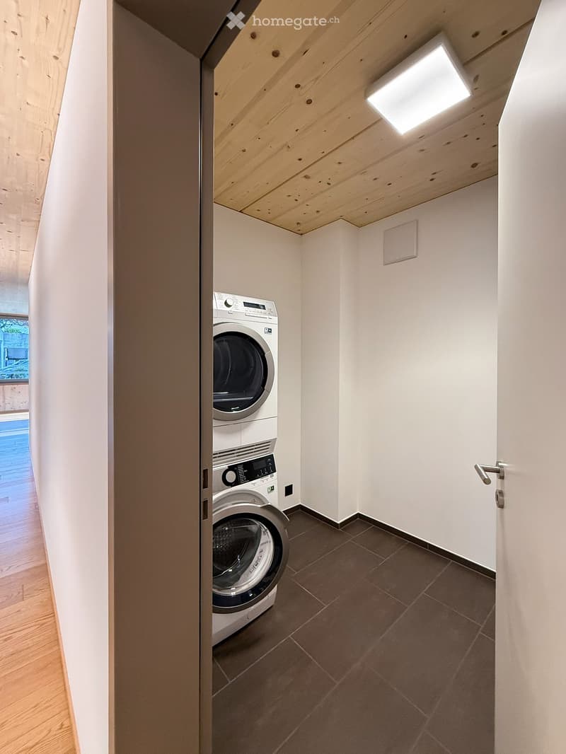 Modern bathroom with white walls, tiled floor, and built-in washing machine and dishwasher.