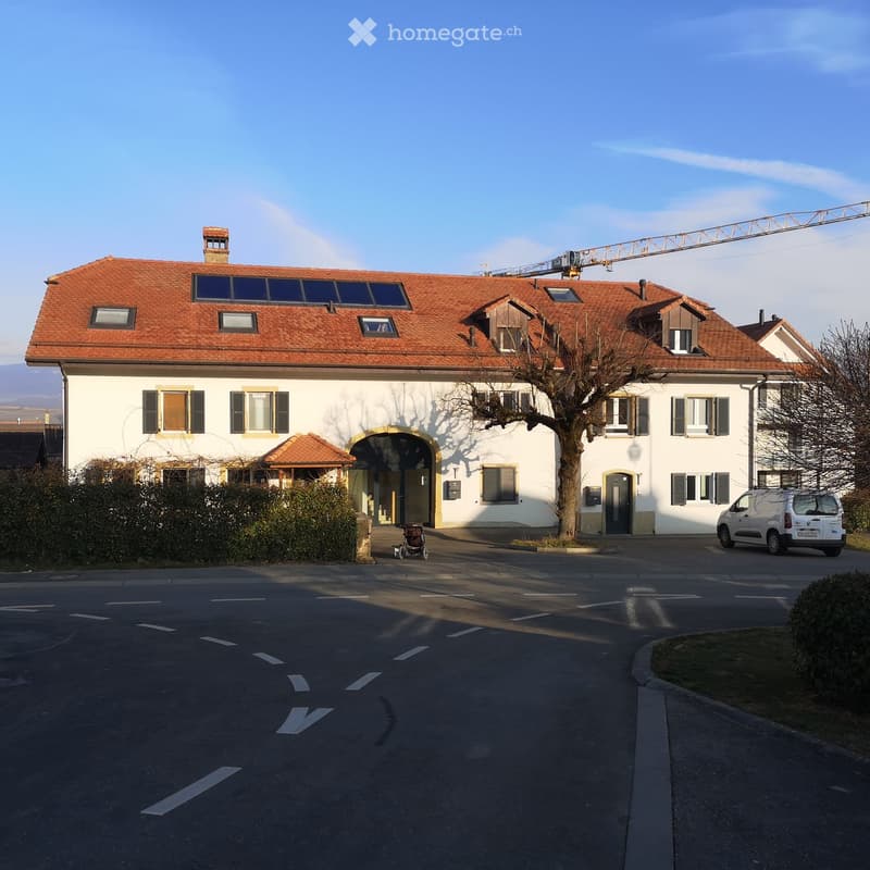 Two-story house with red-tiled roof, white walls, multiple windows, and a small entrance porch. A parked van is visible in the driveway.