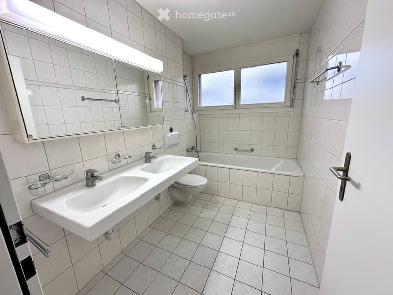 large mirror, double sink, toilet, bathtub, tile flooring, white walls, window