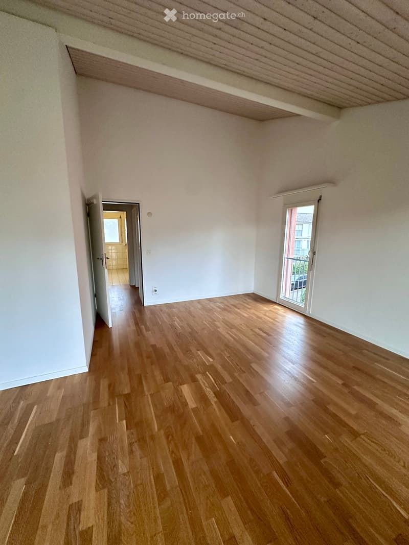 empty room with wooden floor, white walls, sliding glass door, balcony, door, light