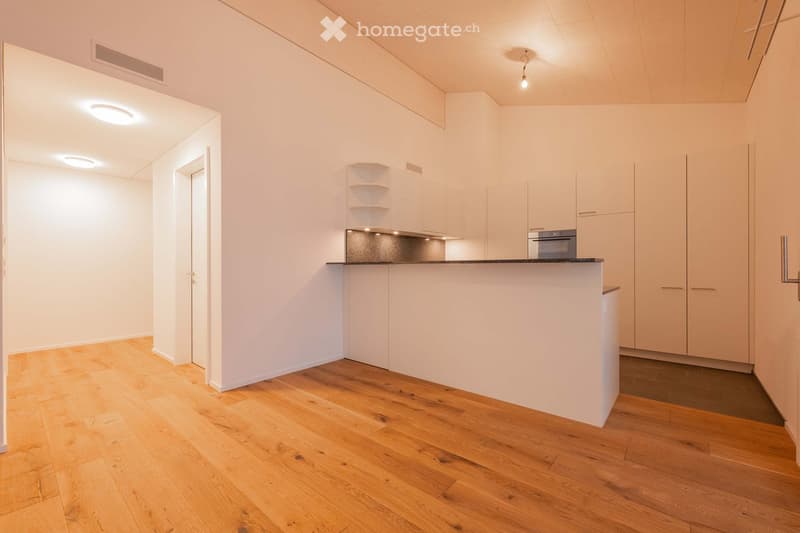Modern kitchen with white cabinets, wooden flooring, and a central island with an oven.