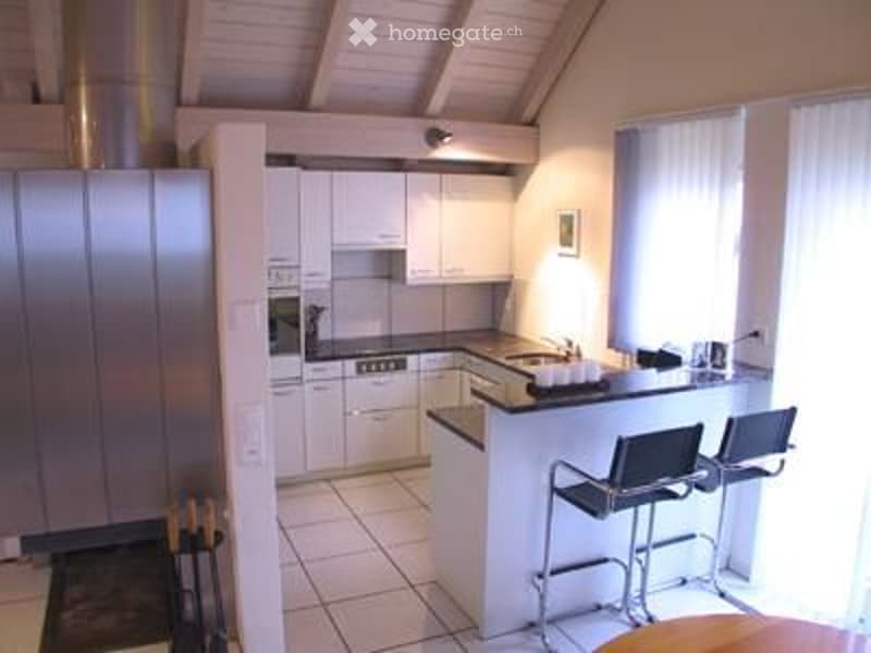 Kitchen. Modern kitchen with white cabinets, stainless steel appliances, island with bar stools, and large windows.