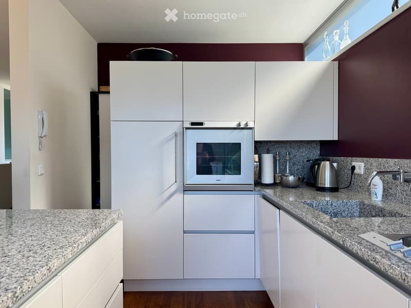 Modern kitchen with white cabinets, granite countertops, stainless steel appliances, and a built-in oven.
