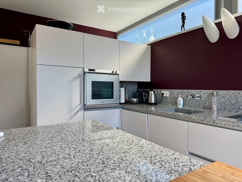 Modern kitchen with white cabinets, granite countertops, stainless steel appliances, and a window overlooking a view.
