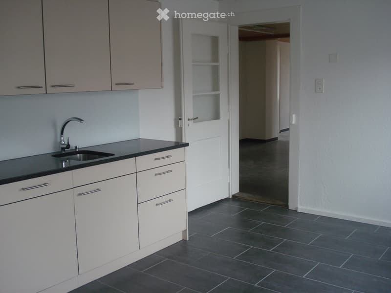 Modern kitchen with white cabinets, black countertop, and stainless steel sink.