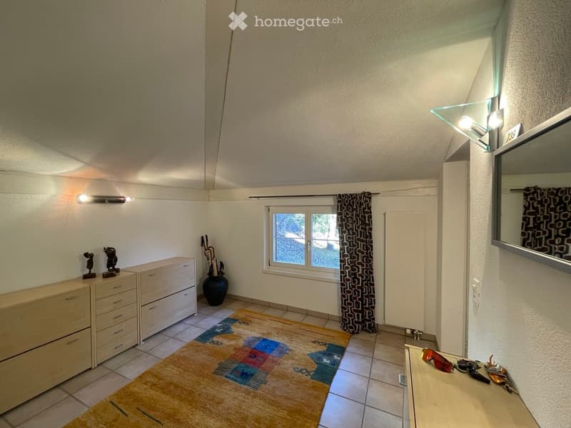 A furnished room with a dresser, vase, rug, mirror, and a small table with keys and sunglasses.