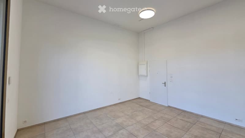 Empty room with white walls, tiled floor, and a single door. No furniture or equipment is present.