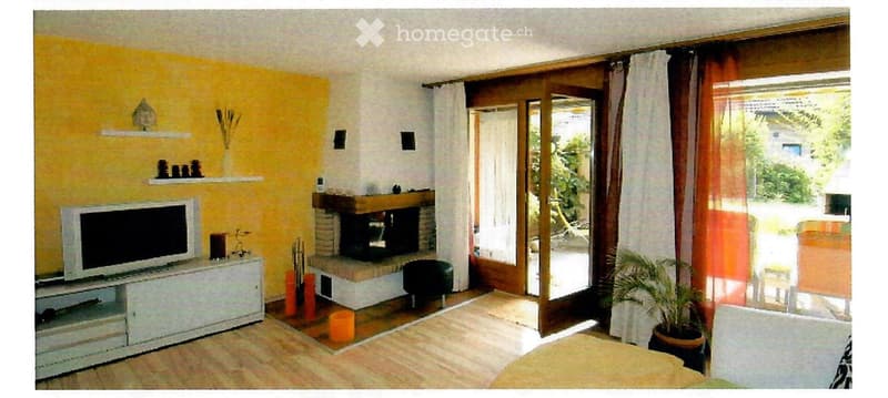 Bright living room with yellow accent wall, fireplace, TV, shelves, and large sliding glass doors leading to outdoor area.