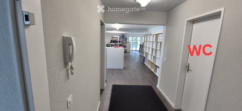 Corridor with a telephone, a power outlet, a door, and a carpet
