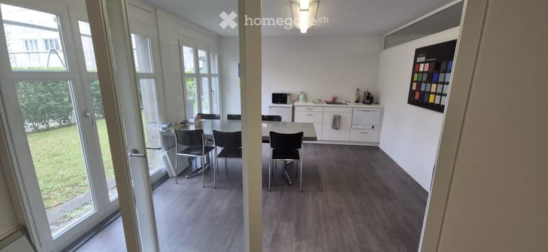 Dining room with table and chairs, kitchen with appliances, large windows