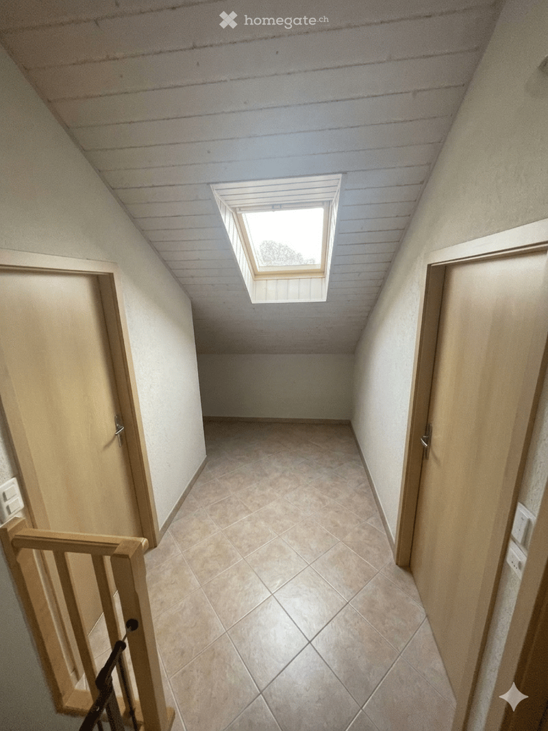 A narrow hallway with tiled flooring, wooden walls, and a skylight window at the far end. The hallway has doors on both sides and a staircase leading upwards.