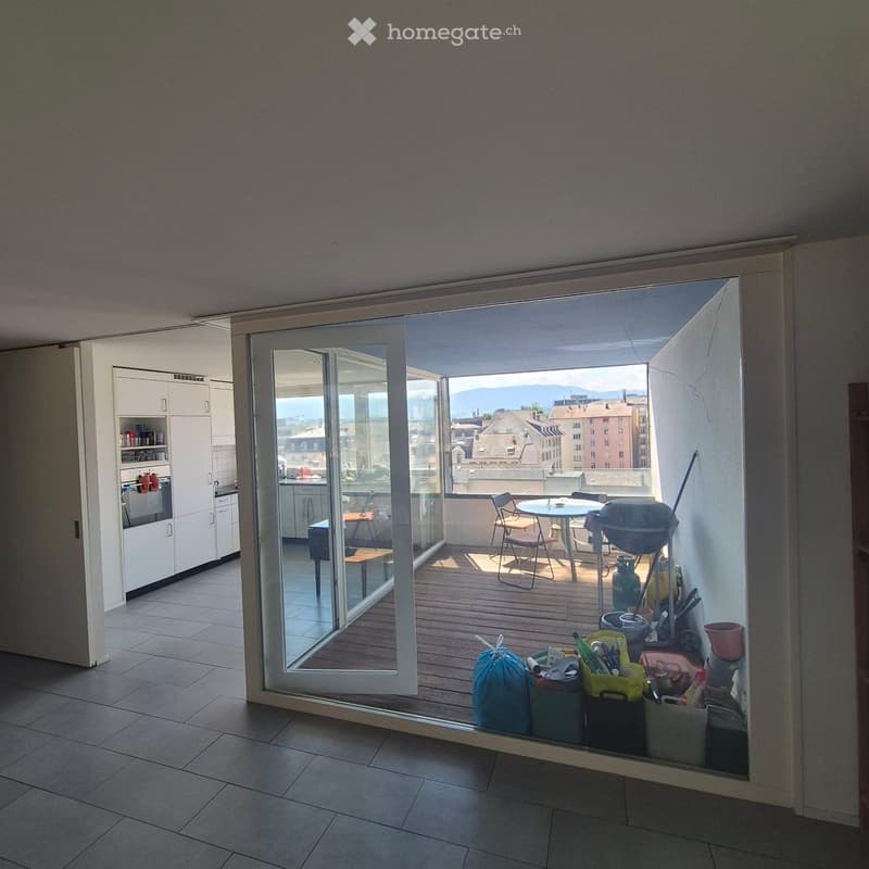 Balcony with wooden decking, glass sliding doors, view of cityscape, table, chairs, grill, and storage bins.