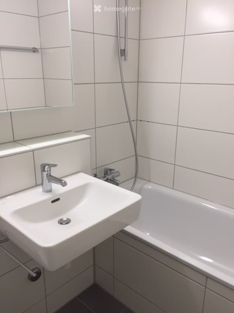 Bathroom with white tiles, white bathtub, white sink, faucet, mirror, shower head