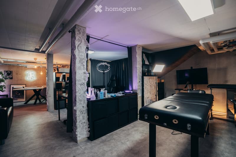 modern room with black leather couch, wooden desk, black and white cabinet, black massage bed, desk with monitor, mirror with lamp