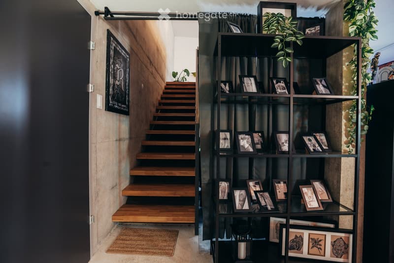 stairs, entryway, rug, black cabinet, framed photos, decorative plant