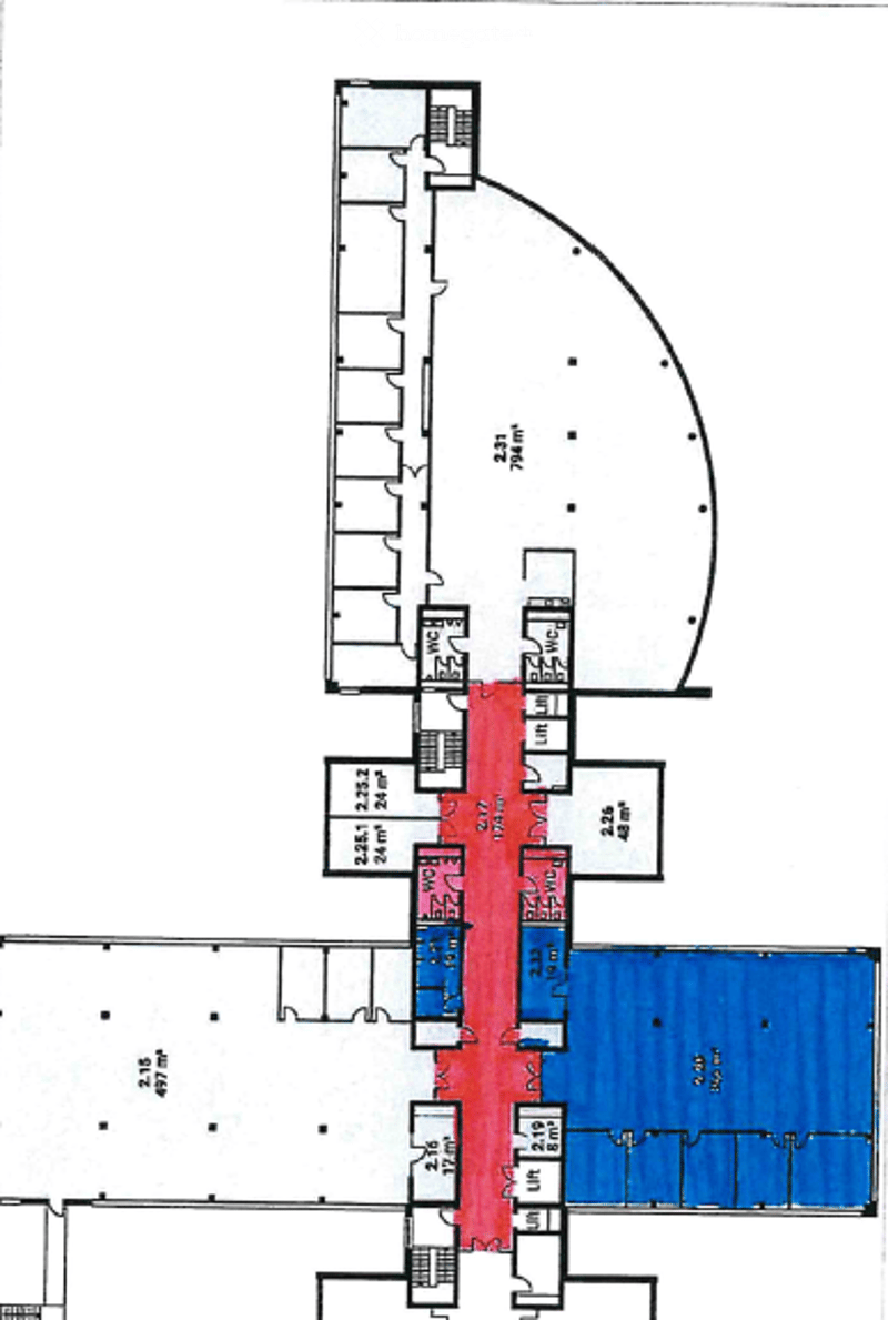 Floor plan of a building with multiple rooms, including a large central area, several smaller rooms, and a prominent curved section on the upper level.