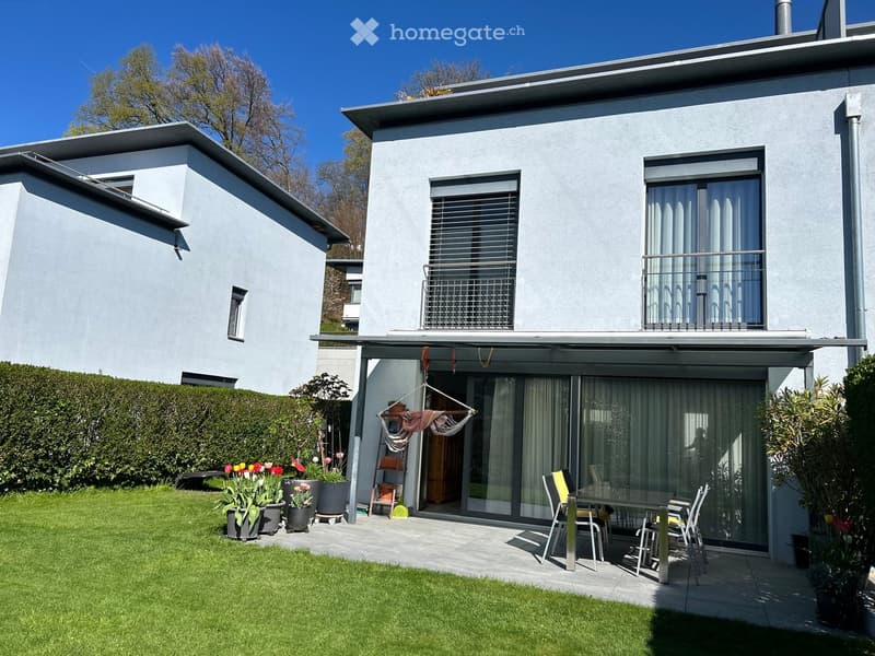 Modern house with a well-maintained garden, patio seating area, and outdoor furniture.