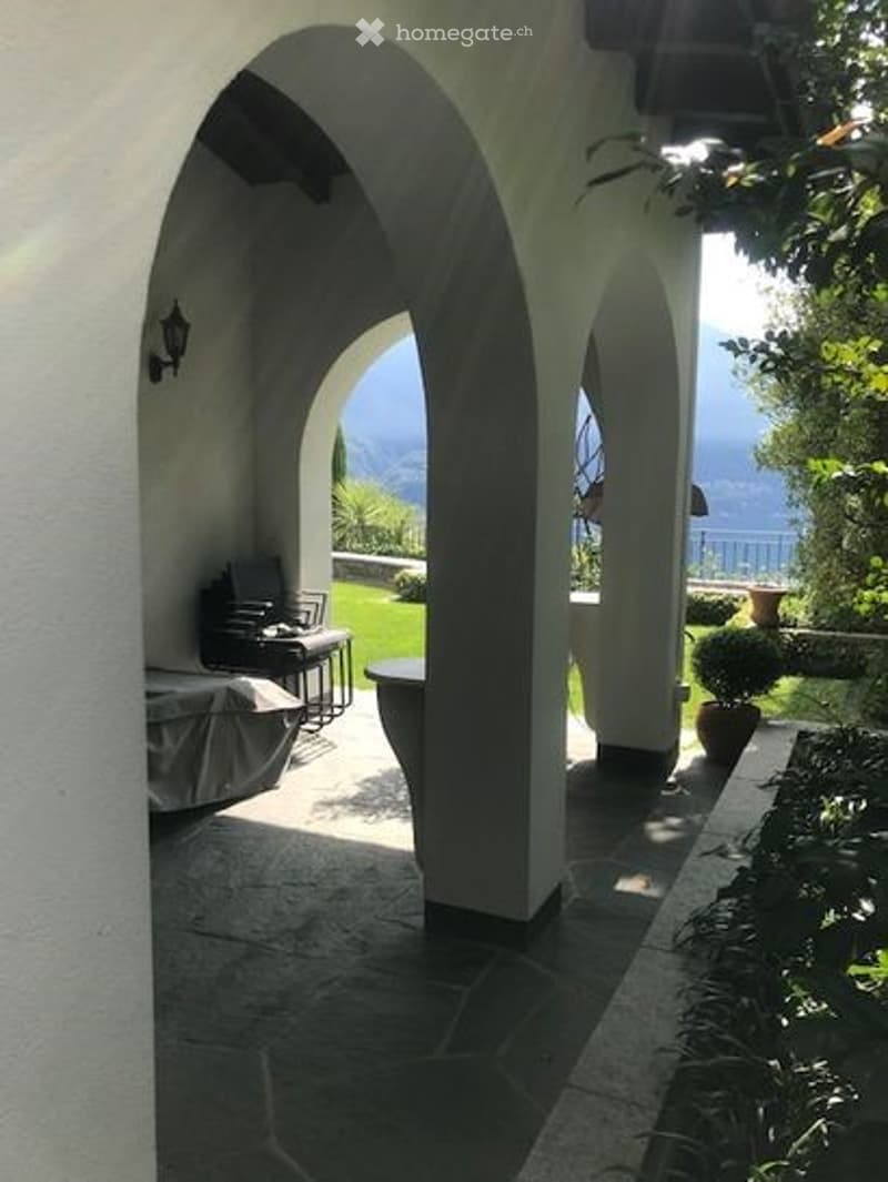 Portico with chairs and table, potted plants, view of the garden and lake