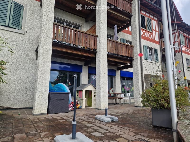 Courtyard area with a wooden balcony, outdoor furniture, and a small playhouse.