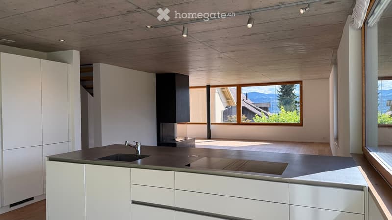 Modern kitchen with white cabinets, dark countertop, and a large window overlooking a scenic view.