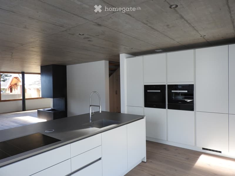 Modern kitchen with white cabinets, black countertops, stainless steel sink and faucet, and built-in ovens.