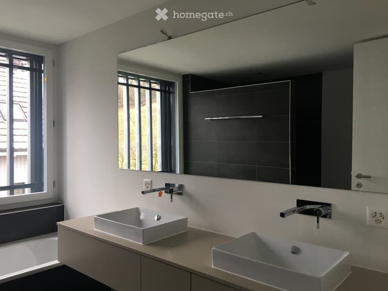 Modern bathroom with two square sinks, sleek faucets, a large mirror, and built-in cabinets.