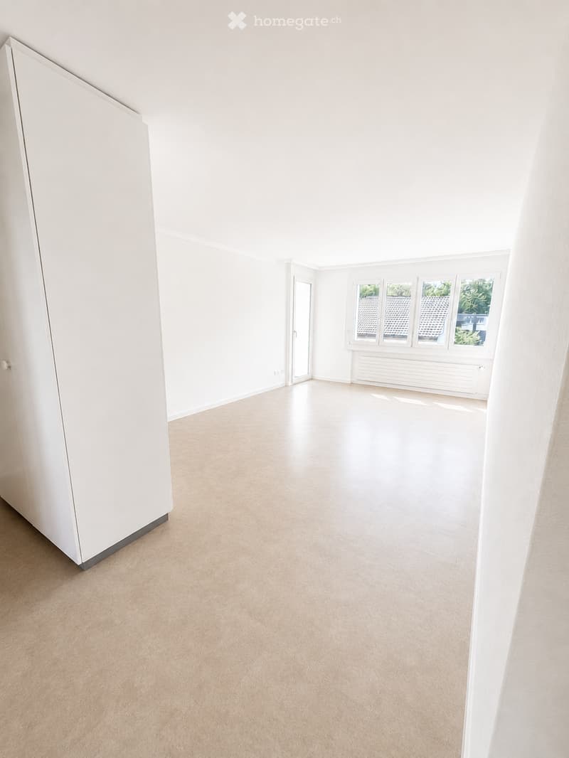 Empty room with light-colored walls, wooden flooring, and large windows with white frames. No furniture or equipment is present.