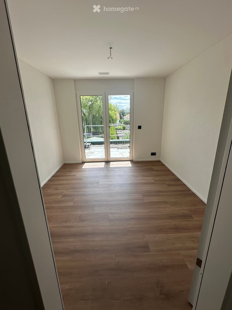 Empty room with wooden floors, white walls, sliding glass doors leading to a terrace