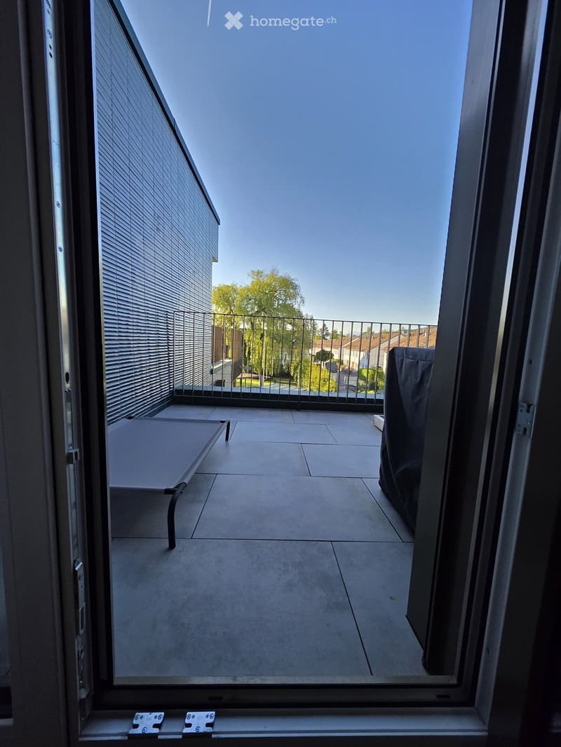 Balcony with tiled floor, metal railing, and a view of the surrounding area and trees.